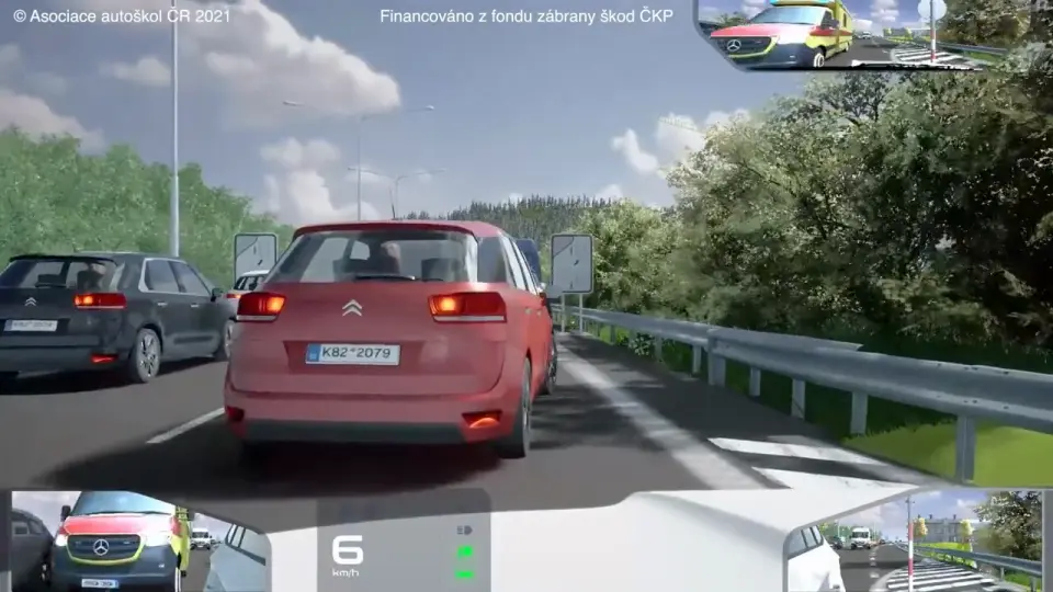 Červené auto těsně před kamerou a v levém dolním zrcátku sanitka přijíždějící zezadu